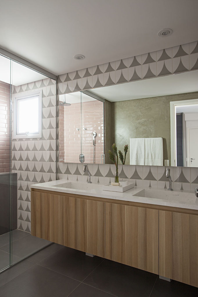 Banheiro planejado com revestimento geométrico e cuba de mármore. 