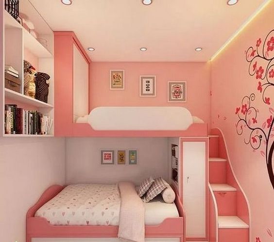 Quarto rosa com duas camas e papel de parede de árvore com flores. 