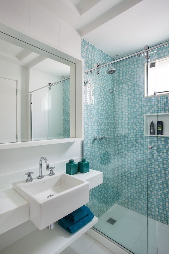 Banheiro todo decorada com tons diferentes de verde e azul.