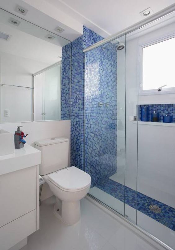 Banheiro com parede do chuveiro e nicho embutido com pastilha azul.