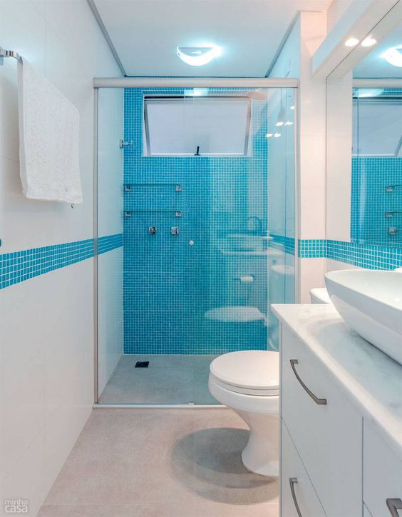 Banheiro todo branco com parede destacada em azul de pastilha.