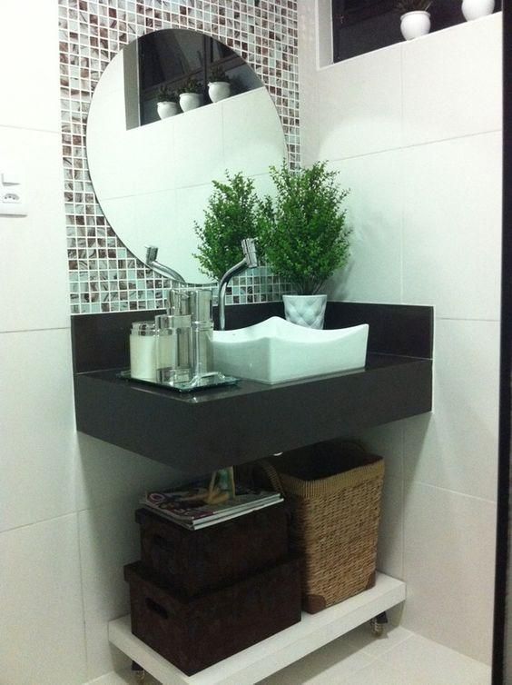 Banheiro decorado com cesto, vaso de planta e pastilha ao redor do espelho.