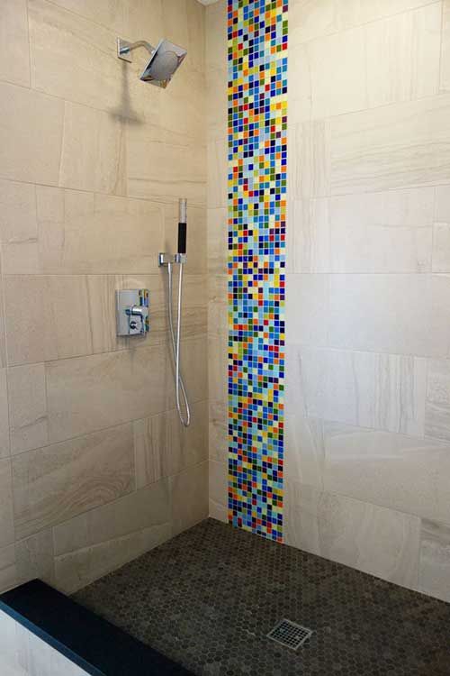 Banheiro com chão de pastilha marrom e uma faixa colorida vertical em uma das paredes.