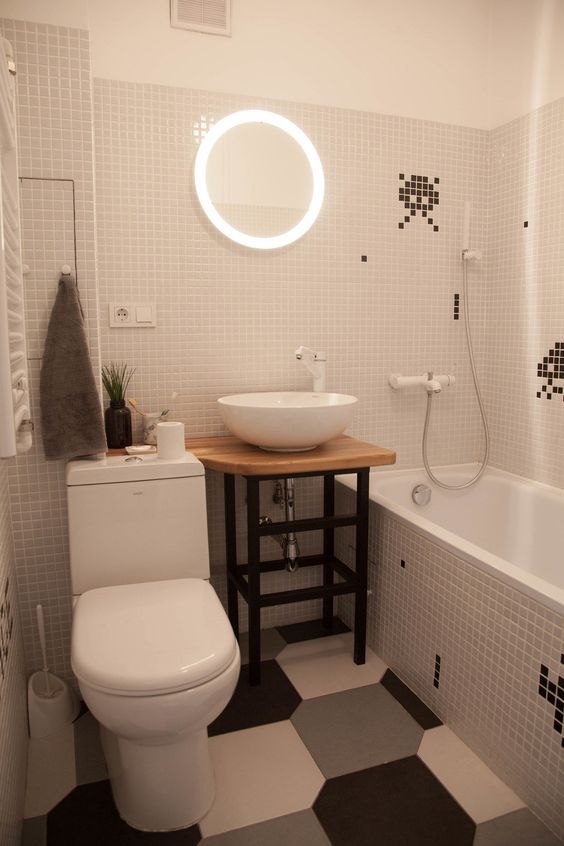 Banheiro revestido com pastilhas brancas e pequenos desenhos pretos.