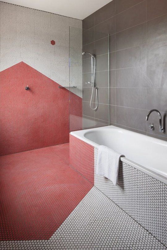 Banheiro com parede, chão e lateral da banheira revestida com pastilha branca e vermelha.