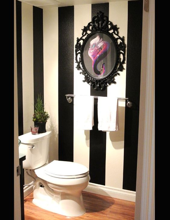 Banheiro com paredes listradas e quadro com desenho e moldura estilo clássico.