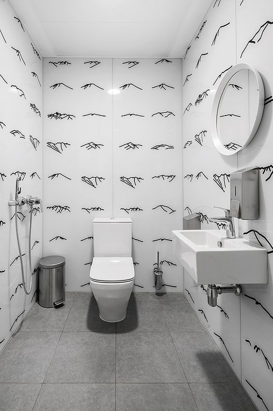 Banheiro branco com desenhos de traços finos pretos nas paredes.