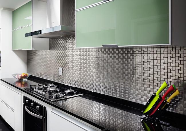 Cozinha moderna com armários verdes e pastilhas pretas.