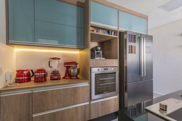 Cozinha azul com armários em madeira.