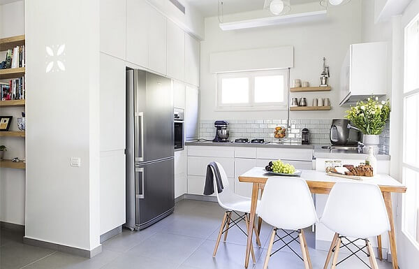Cozinha em L com armários brancos e decoração minimalista.