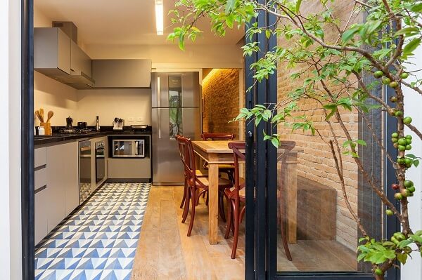 Cozinha moderna com armários em L e piso colorido.