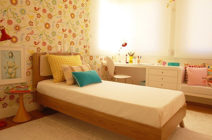 Quarto de menina com cama de madeira e papel de parede decorado.