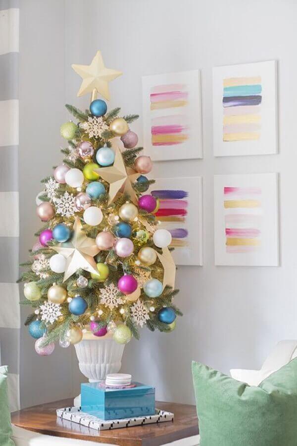 Decoração de natal para sala pequena com árvore colorida na mesa lateral.