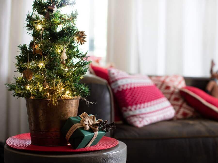 Decoração de natal para sala pequena com árvore e almofadas temáticas.
