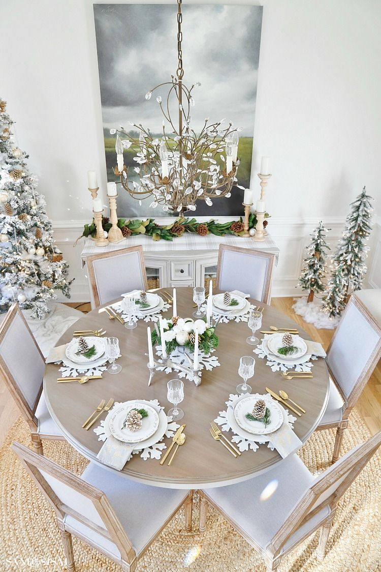 Decoração de natal para sala de jantar com árvores decoradas, talheres dourados e jogo americana temática.