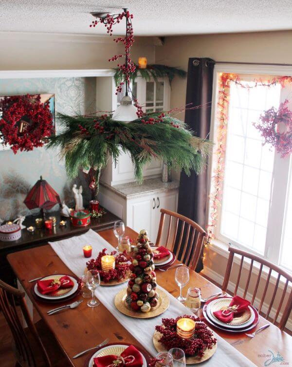 Decoração de natal para sala de jantar com árvore de bola de natal, velas, guirlandas e guardanapos.