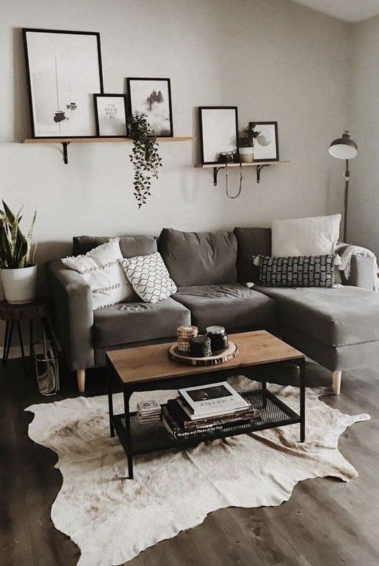 Sala com sofá cinza em "L" e quadros em preto e branco.