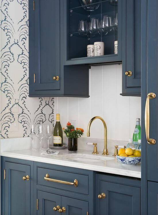 Cozinha elegante com armário azul e papel de parede discreto.