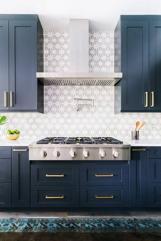 Cozinha com armários azuis clássicos com papel de parede discreto.