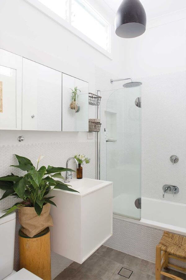 Banheiro branco decorado com plantas.