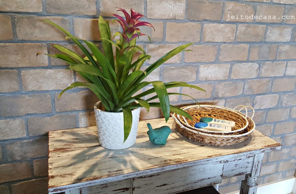 Vaso de bromélia decorando mesa rústica.