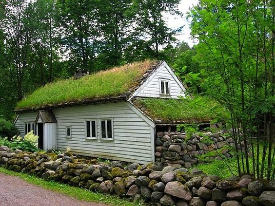 casa branca de madeira rústica com teto verde e pedras na lateral