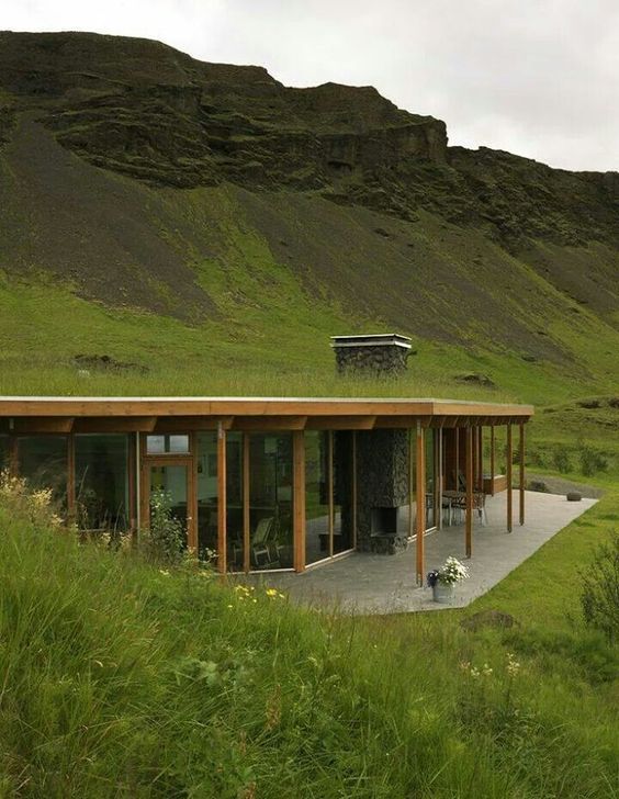 casa integrada com paredes de vidro em montanha em teto de vegetação